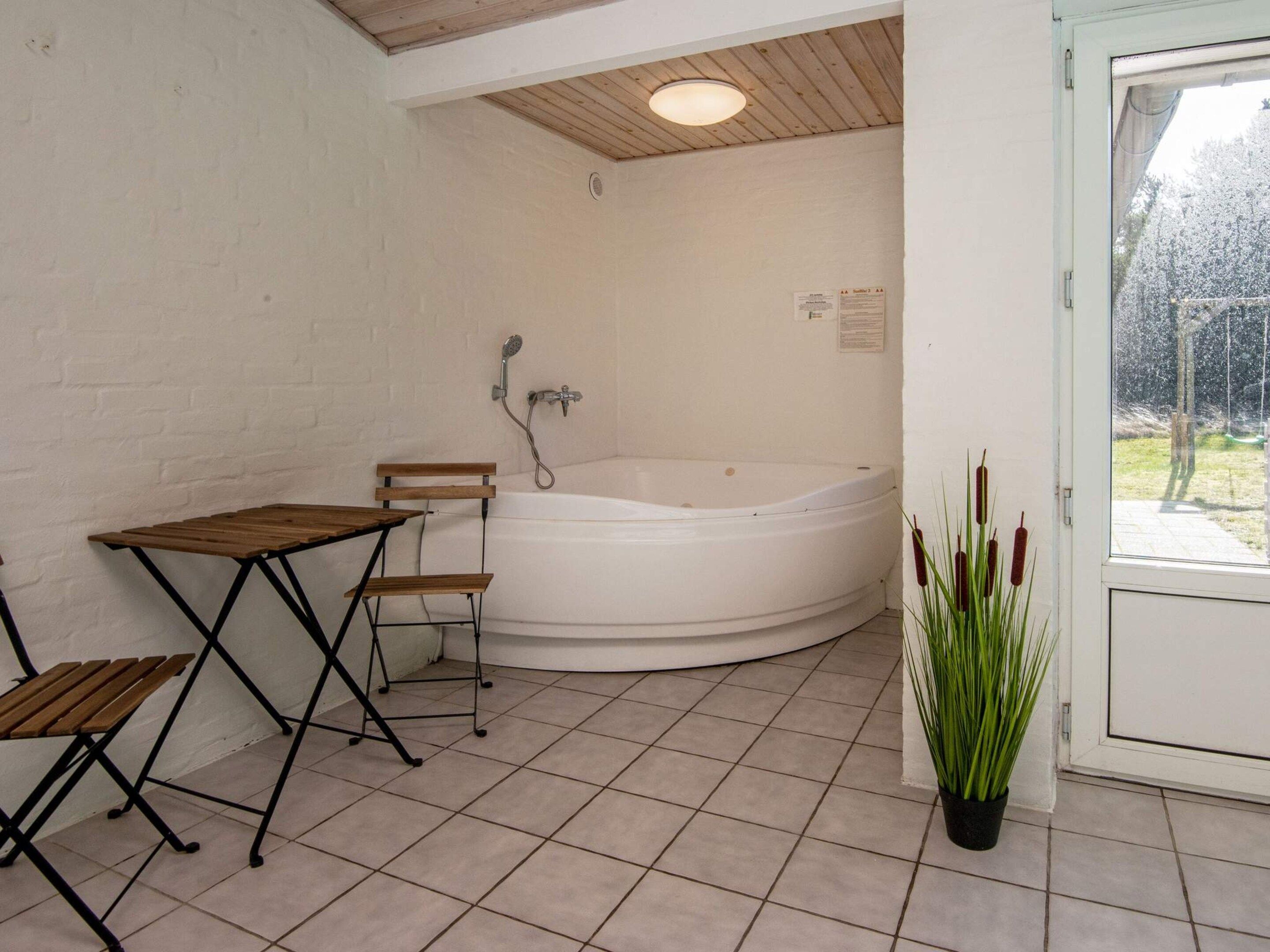 A bathroom with a bathtub, a shower, and a small table with chairs.