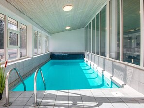 An indoor swimming pool with clear blue water, surrounded by large windows and a tiled floor. - 4 Star Holiday Home in Romo (Rømø)