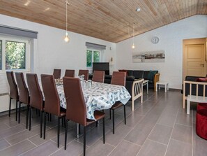 A dining area with a table set for six, surrounded by chairs, a sofa, and a television. - 4 Star Holiday Home in Romo (Rømø)