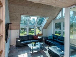 A modern living room with a sloped ceiling, large windows, and leather sofas. - 4 Star Holiday Home in Romo (Rømø)