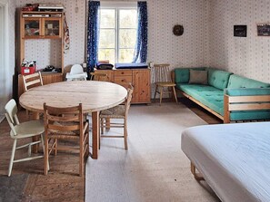 A cozy room with a wooden dining table, chairs, a green sofa, and a bed. - 4 Person Holiday Home in Malung-by Traum (Malung)