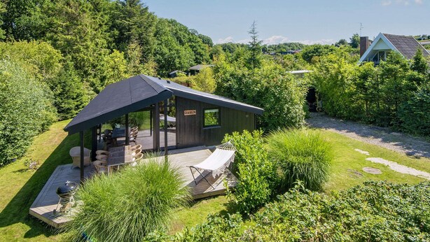 Un chalet isolé, doté d’un patio couvert, entouré d’une végétation luxuriante et surplombant un ciel dégagé.