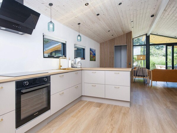 Een moderne keuken met een inbouwoven, witte kastjes en een houten aanrecht.