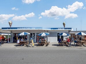 Outdoor seating areas with umbrellas, a beachside food establishment, and ice cream cones.