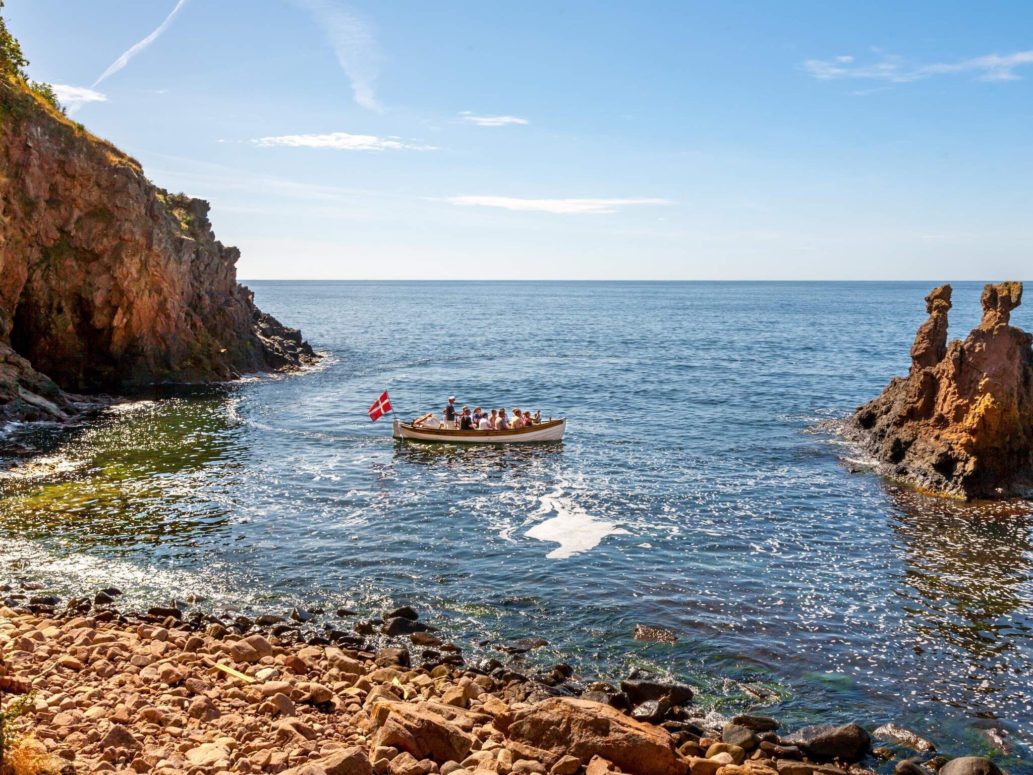 A rocky shoreline with a boat carrying passengers.