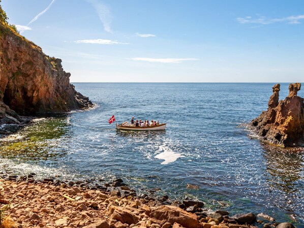 A rocky shoreline with a boat carrying passengers.