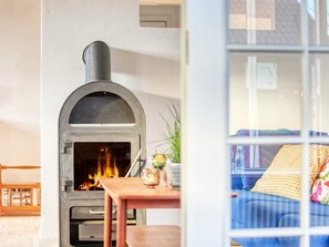 Une pièce avec un poêle à bois, un canapé et une fenêtre.