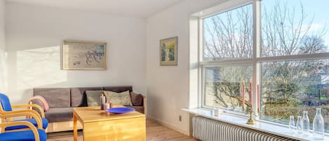 A living room with a sofa, chairs, a coffee table, and a large window with a view of trees.