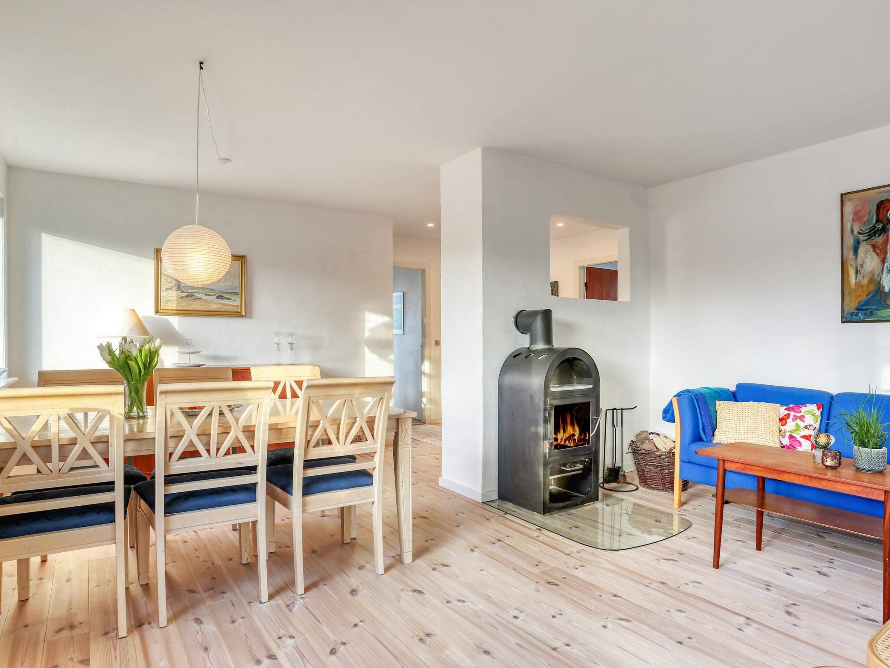 Una sala moderna con una mesa de comedor de madera, sofá azul y estufa de leña.