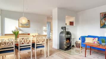 Una sala moderna con una mesa de comedor de madera, sofá azul y estufa de leña.