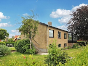 A two-story brick house with a small front yard, a tree, and a clear sky. - 6 Person Holiday Home in Strandby (Strandby)