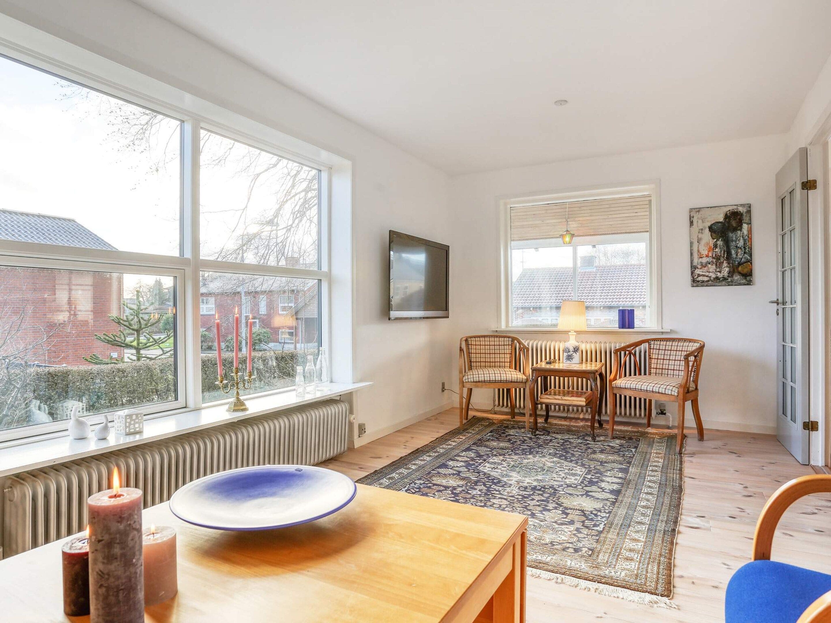 Une pièce comprenant une table à manger, des chaises, un radiateur, une fenêtre donnant sur un beau paysage et un tableau accroché au mur.