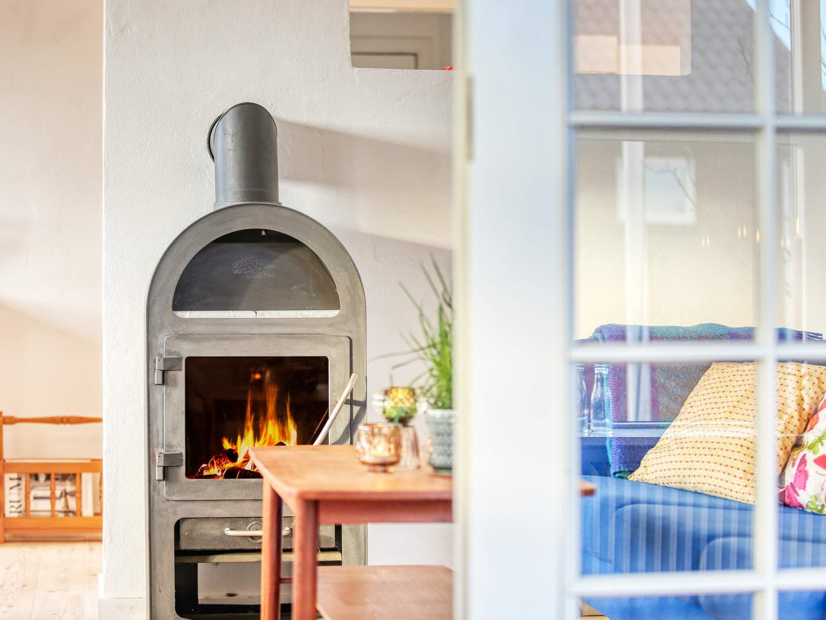 Una habitación con chimenea, un sofá y una mesa con un vaso.
