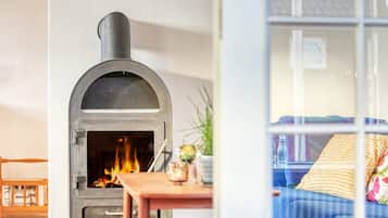 Una habitación con chimenea, un sofá y una mesa con un vaso.