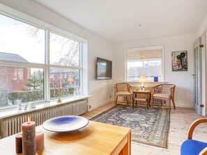 A room with a large window, a table with candles, a radiator, and a blue chair. - 6 Person Holiday Home in Strandby (Strandby)