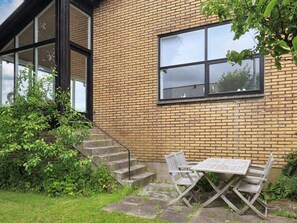 Un bâtiment en briques doté d’une grande fenêtre, d’un escalier et d’une table avec des chaises à l’extérieur.