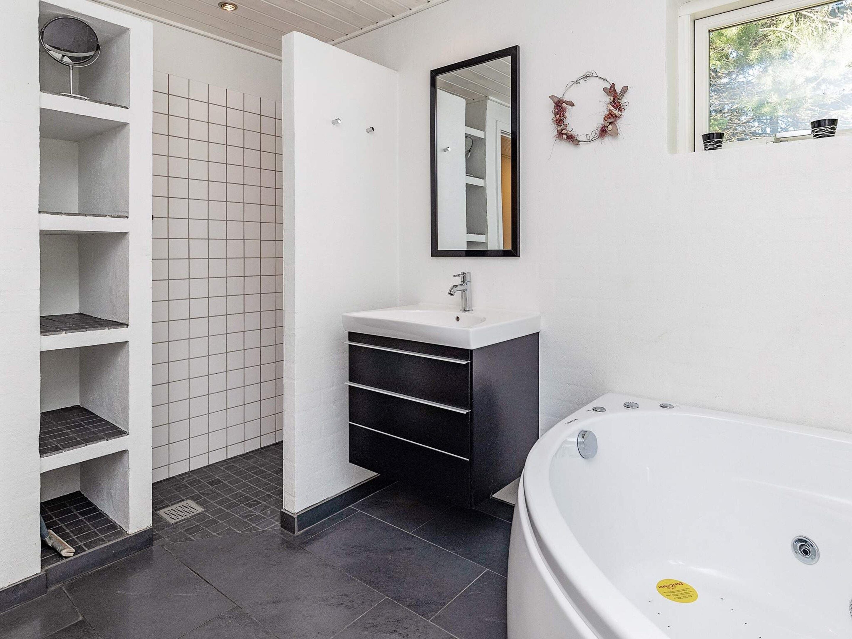 A modern bathroom with a white vanity, a large bathtub, and a shower area.