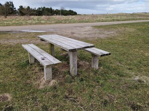 Ein Holztisch mit Bänken in einer grünen Wiese.