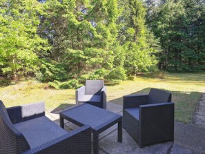 Outdoor wicker furniture arranged on a concrete patio with a grassy area and trees in the background. - 6 Person Holiday Home in Hojslev (Hojslev)