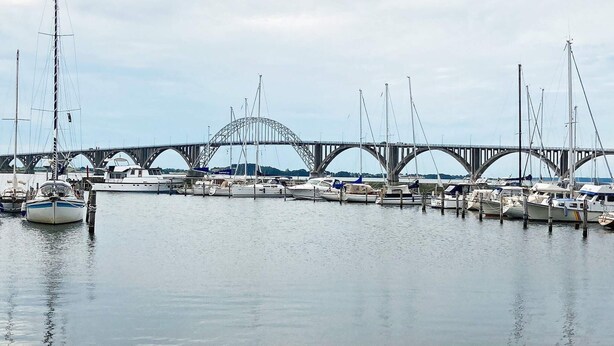 Un port de plaisance où des bateaux sont amarrés sous un grand pont.