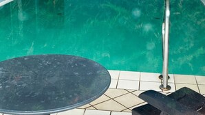 Une piscine à l’eau claire, dotée d’une rambarde de sécurité en métal et d’un sol carrelé.