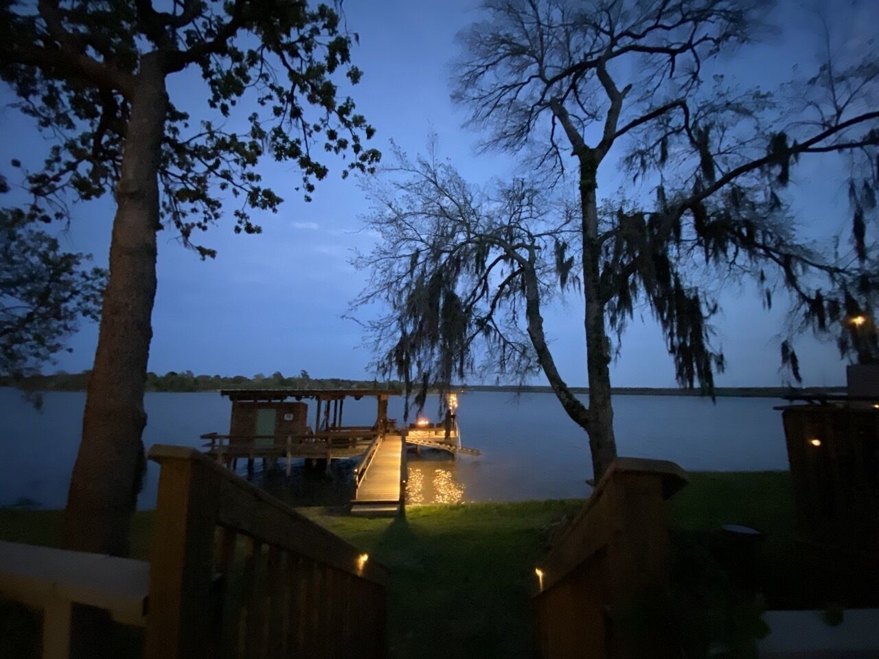 A lakeside cabin with a dock extending into the water, surrounded by trees.
