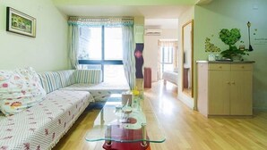 A living room with a sofa, a glass coffee table, and a cabinet. - Keluowei Hotel (Shenzhen)