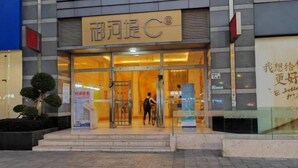 A building entrance with a glass door, signage, and a person entering. - Keluowei Hotel (Shenzhen)