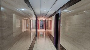A long, polished hallway with reflective floors and walls, leading to a central door. - Keluowei Hotel (Shenzhen)