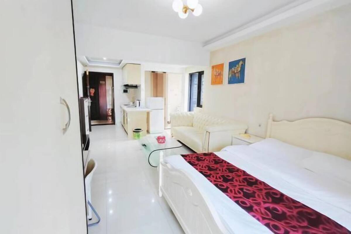 Una habitación de hotel moderna con una cama grande, un sofá, un escritorio y una kitchenette.