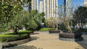 A paved walkway with landscaped areas and tall buildings in the background. - Keluowei Hotel (Shenzhen)