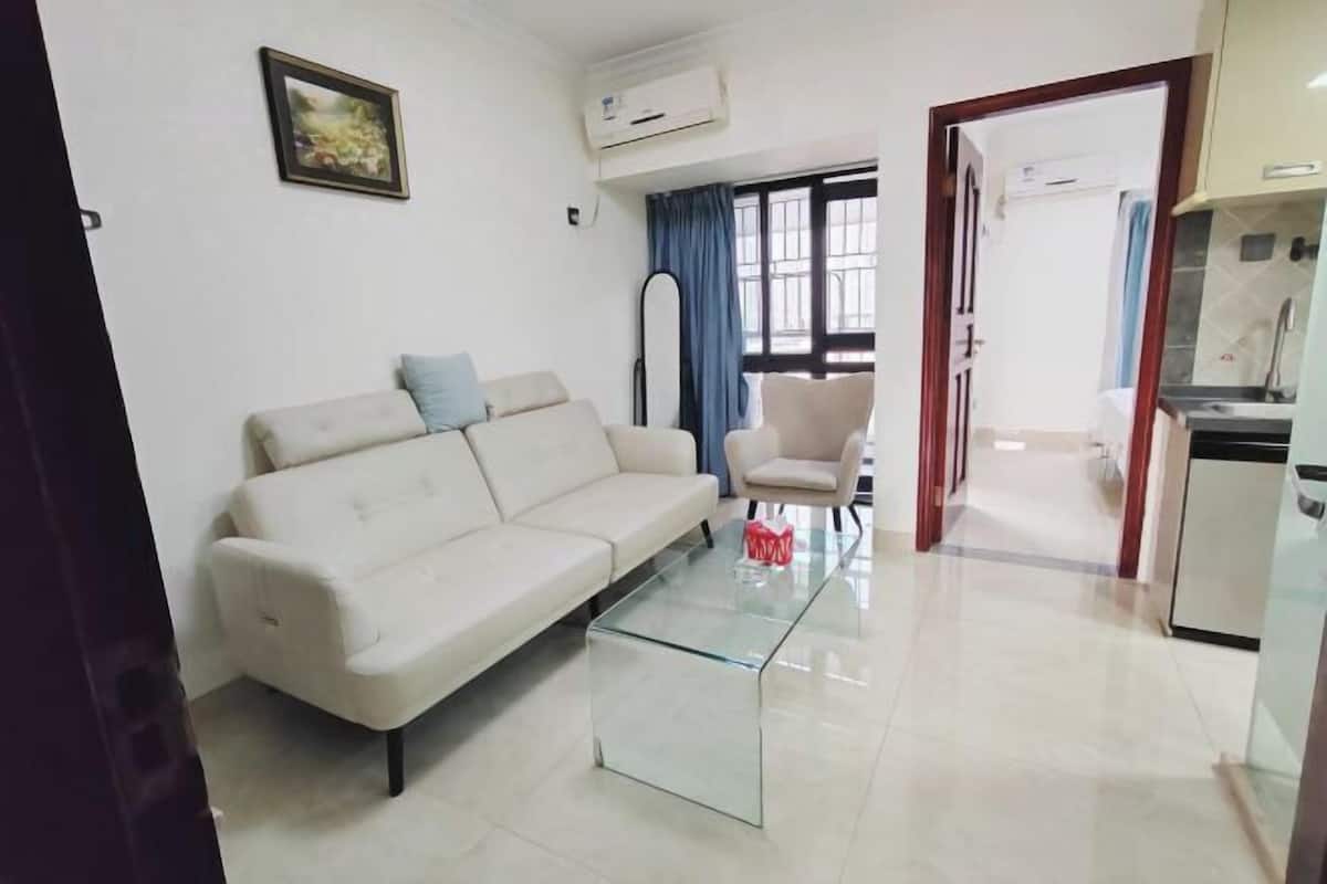 Una sala de estar con un sofá, una mesa de centro de vidrio y un cuadro en la pared.
