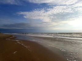 Una playa con una amplia orilla arenosa y olas suaves.