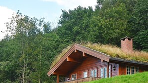 Eine Holzhütte mit geneigtem Dach, einem Schornstein und einer Veranda mit Geländern.