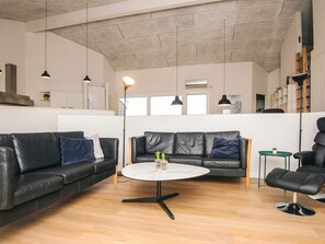 A spacious living area with a large black leather sofa, a round coffee table, and a black leather armchair. - 12 Person Holiday Home in Ebeltoft (Ebeltoft)