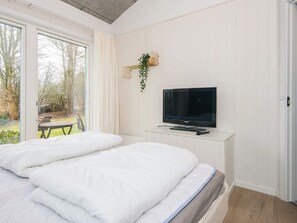 A bedroom with a bed, a TV, and a window overlooking a garden. - 12 Person Holiday Home in Ebeltoft (Ebeltoft)