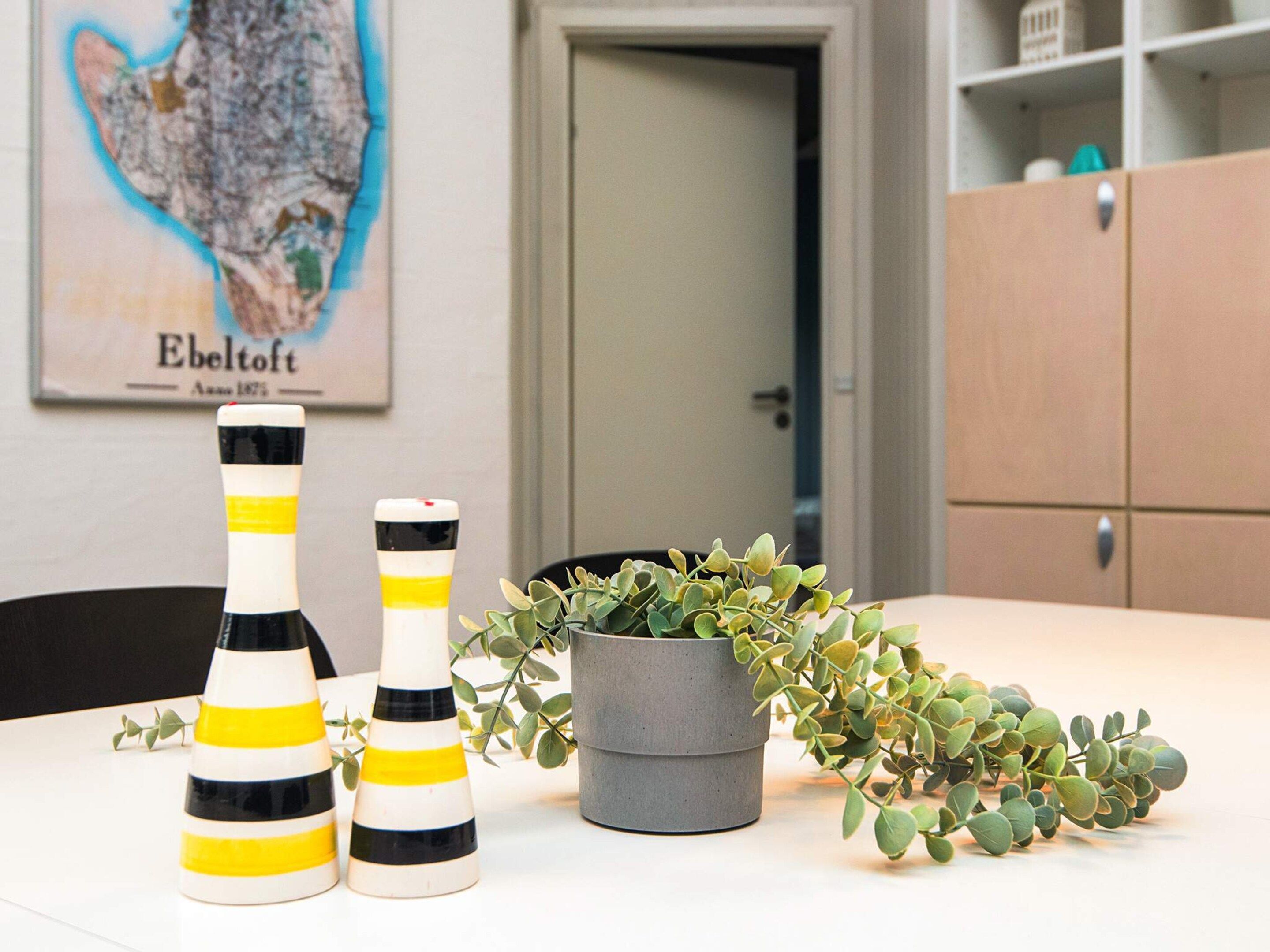 Una mesa con velas a rayas, una planta en maceta y un mapa en la pared.