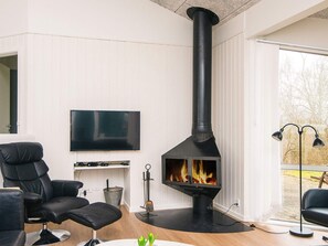 Una sala de estar moderna con un estufa de leña negra, un televisor de pantalla plana y sillones de cuero negro.
