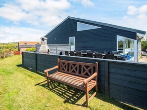 A modern outdoor seating area with a wooden bench, a barbecue grill, and a pool. - 12 Person Holiday Home in Ebeltoft (Ebeltoft)