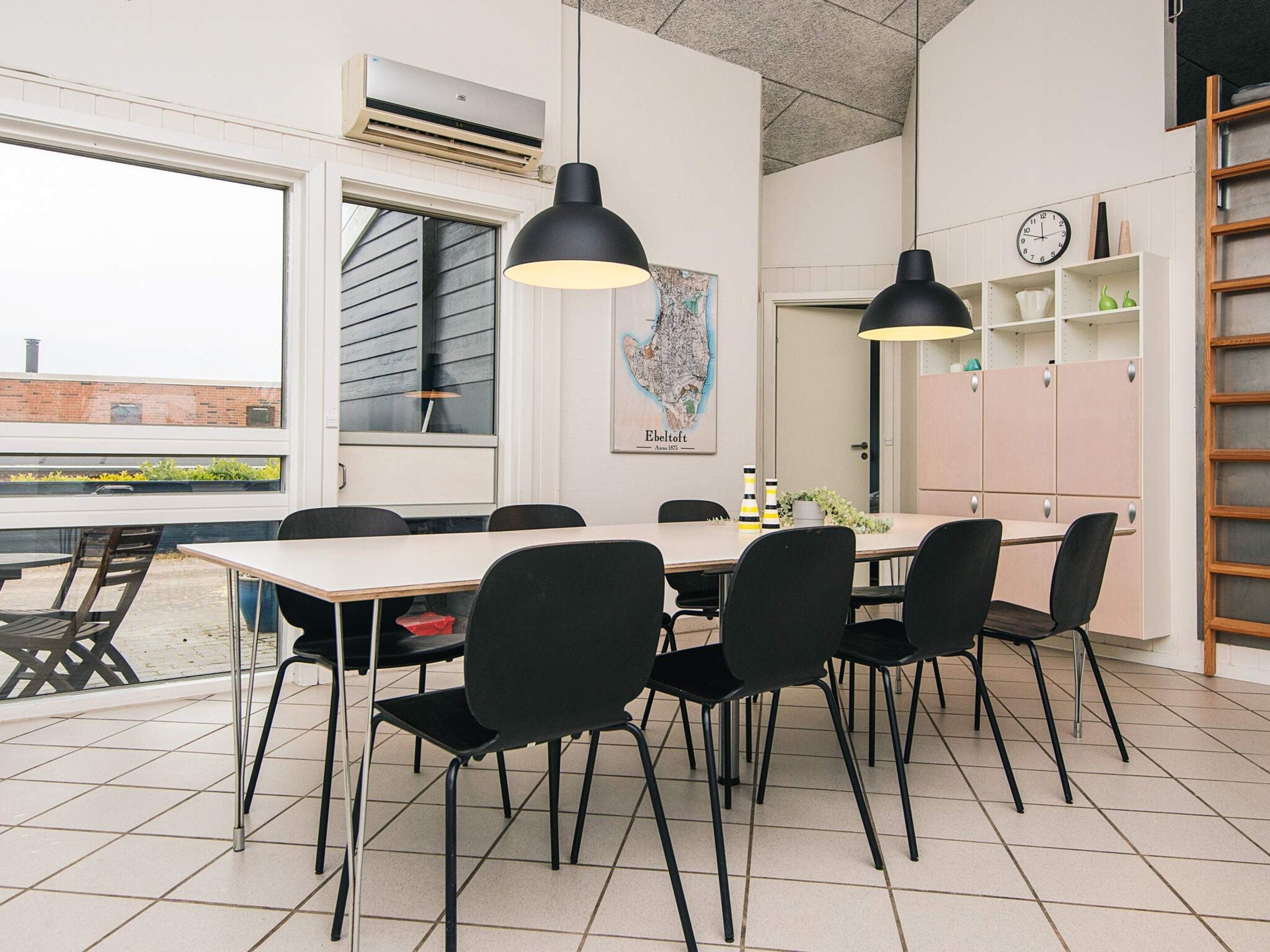 A modern dining area with a large table and black chairs, a map on the wall, and a clock on the wall.