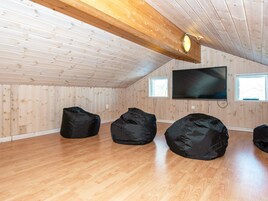 A room with wooden walls, a sloped ceiling, a flat-screen TV, and three bean bags.