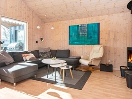 Una sala moderna con un sofá seccional, una mesa de centro redonda y una chimenea.