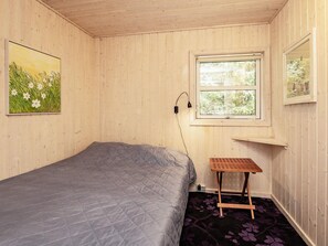 A room with a bed, a window, a wall-mounted lamp, and a painting. - 8 Person Holiday Home in Blokhus (Blokhus)