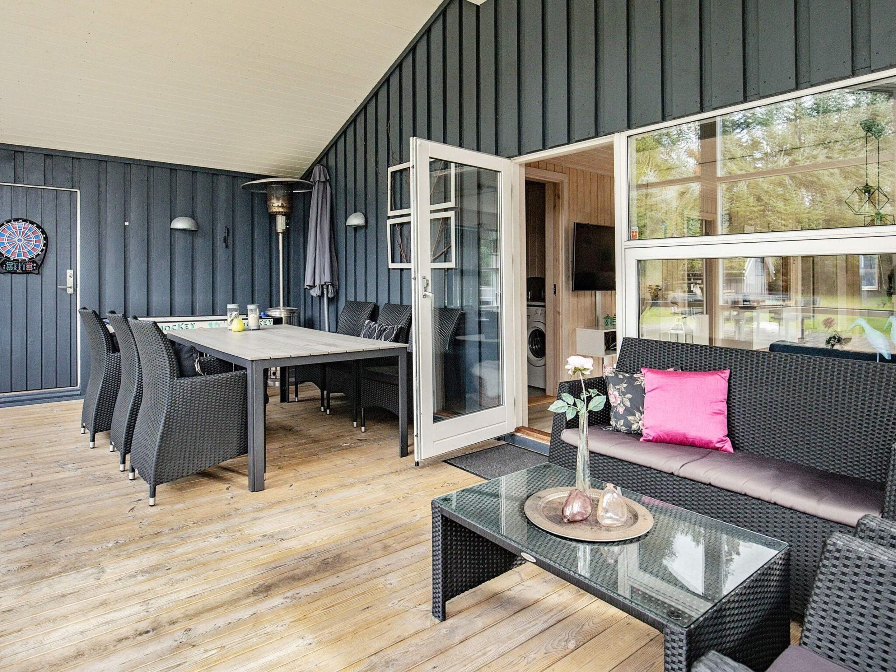 A room with a dining table, chairs, a sofa, and a glass coffee table.