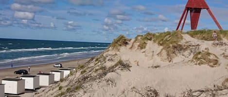A beach with a red structure, white buildings, and the ocean.