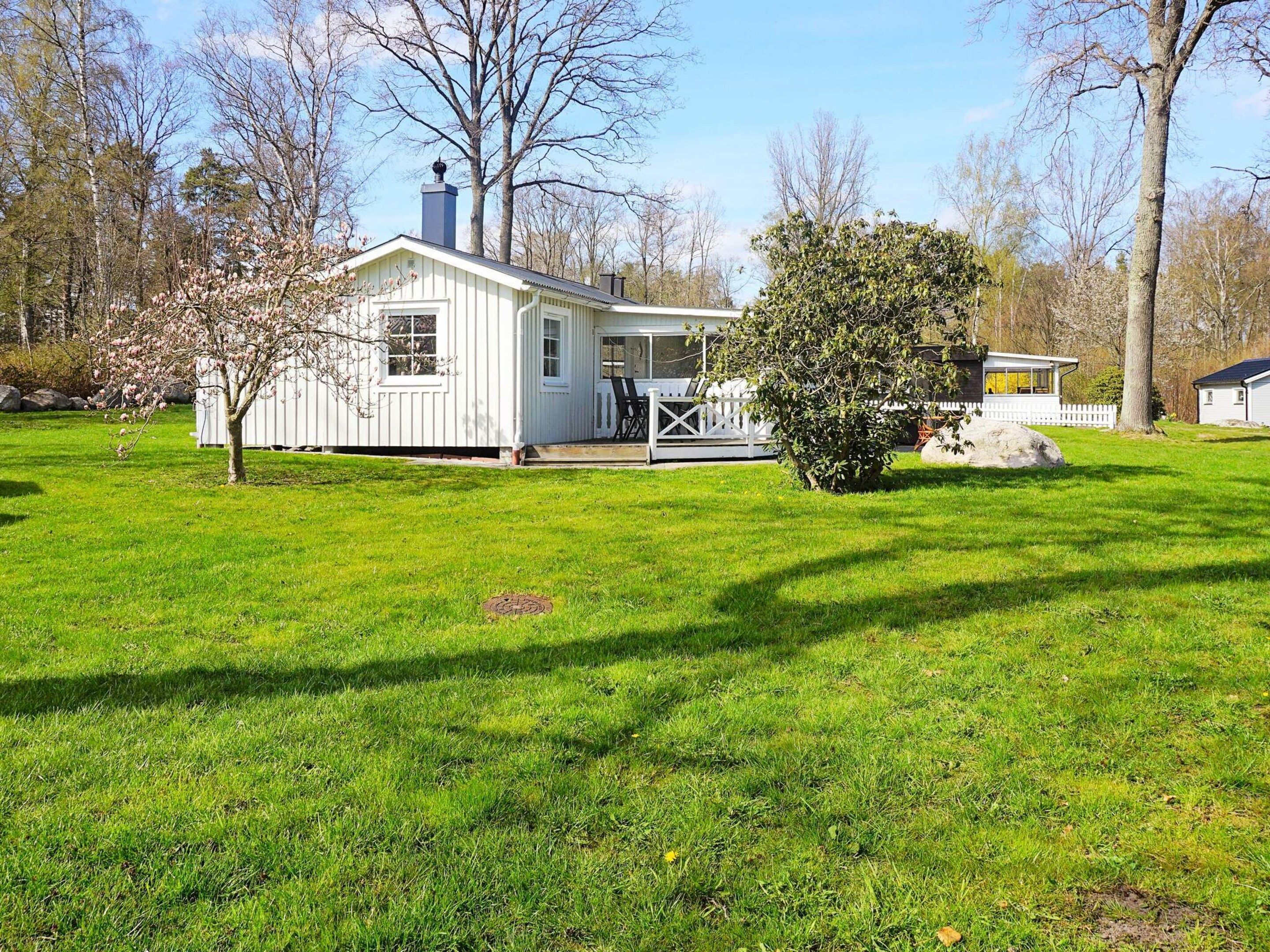 A white single-story house with a porch, surrounded by a well-maintained lawn and trees.