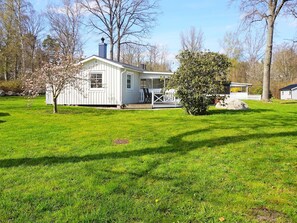 A white house with a porch, surrounded by a grassy yard and trees.