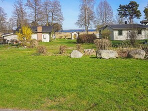 A residential area with houses, a grassy lawn, and a body of water in the background.