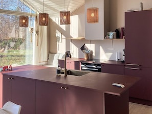 A modern kitchen with a central island, pendant lighting, and a view of the outdoors. - 5 Star Holiday Home in Vaeggerlose (Vaeggerlose)