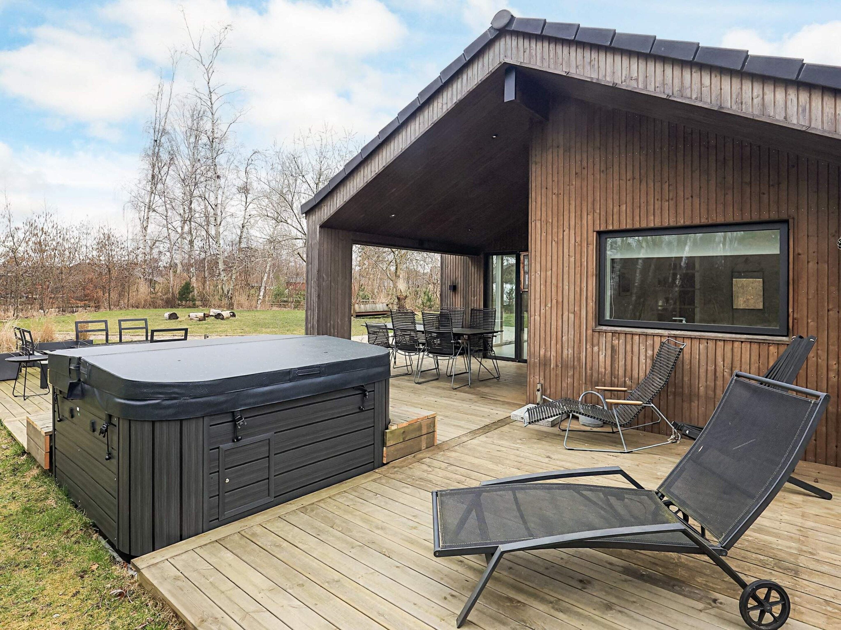 A hot tub on a wooden deck, outdoor furniture, and a covered patio area.